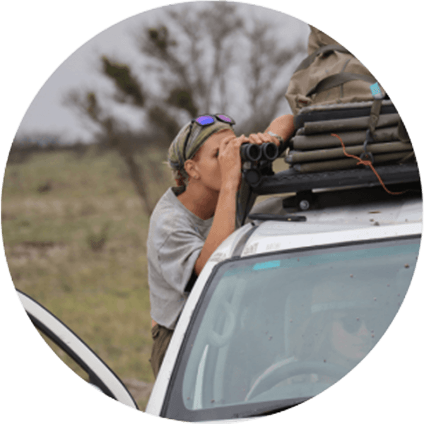 A female Round River student uses binoculars to spot wildlife.